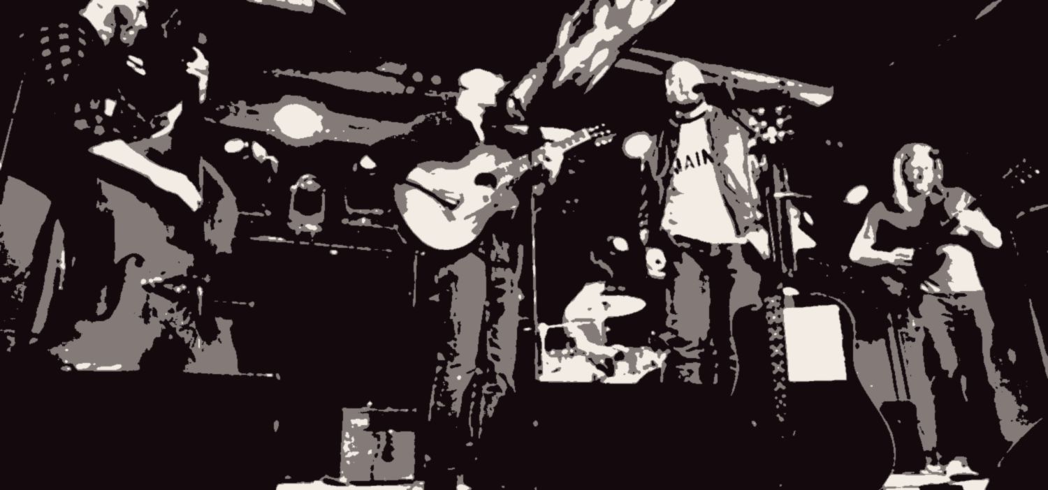 The whole band on a small stage under the ductwork: upright bass, acoustic guitar, a singer, drums and electric guitar.